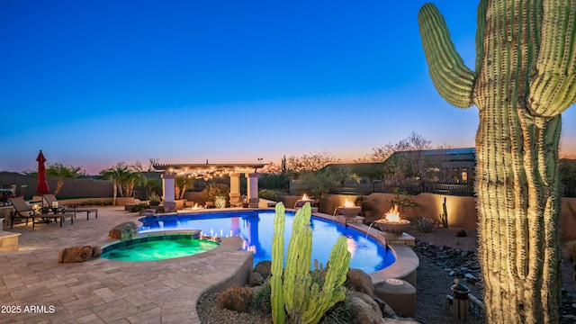 pool at dusk with an in ground hot tub, a patio area, and a fire pit