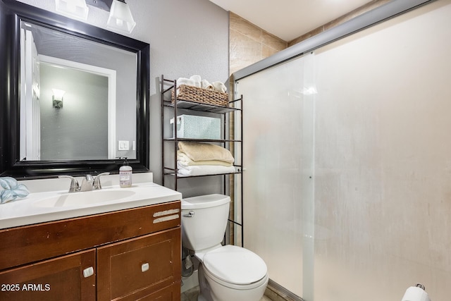 bathroom with vanity, a shower with door, and toilet