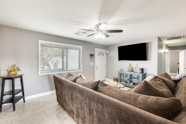 living room featuring ceiling fan and a textured ceiling