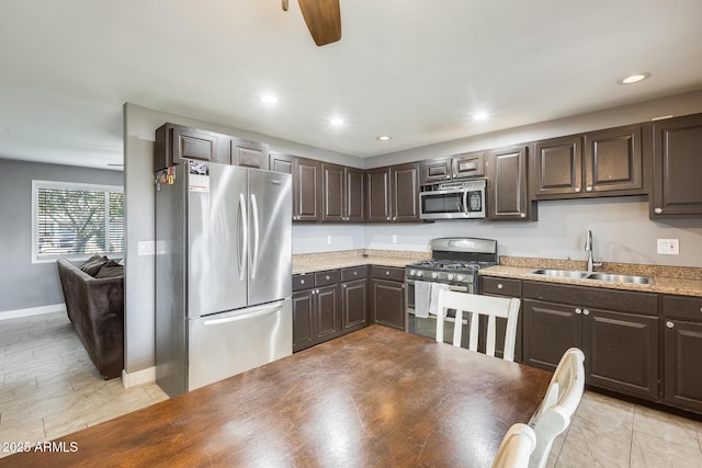 kitchen featuring dark brown cabinetry, sink, light tile patterned floors, and stainless steel appliances