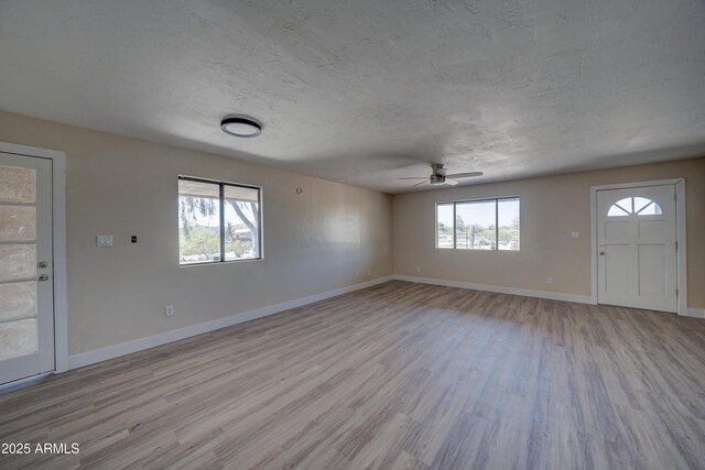 unfurnished living room with a ceiling fan, wood finished floors, and baseboards
