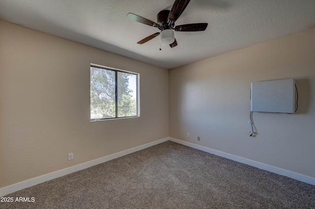 carpeted empty room featuring ceiling fan and baseboards