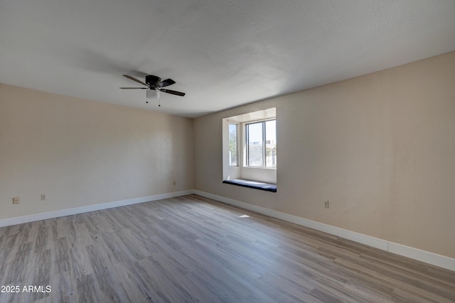empty room featuring wood finished floors, a ceiling fan, and baseboards