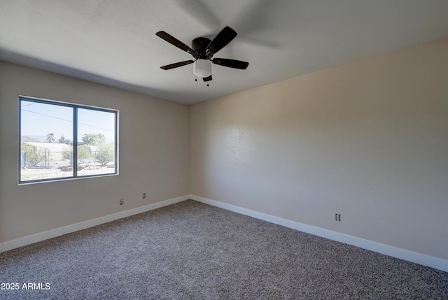 carpeted spare room featuring baseboards and a ceiling fan