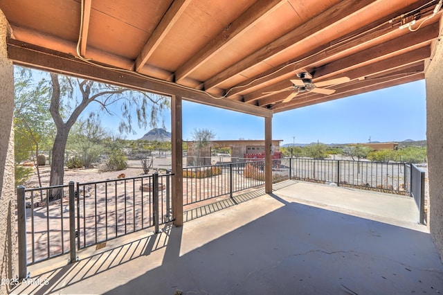 view of patio with a mountain view, a ceiling fan, and fence
