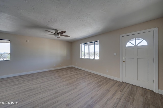entrance foyer featuring light wood-style floors, baseboards, ceiling fan, and a textured ceiling