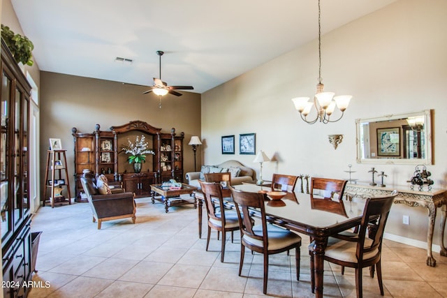 dining room with light tile patterned flooring, a towering ceiling, and ceiling fan with notable chandelier