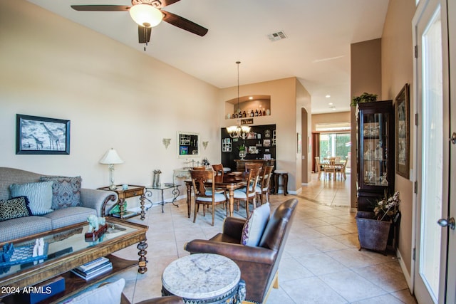 tiled living room with ceiling fan with notable chandelier