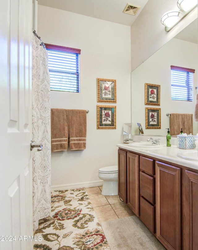 bathroom with vanity, a wealth of natural light, tile patterned floors, and toilet