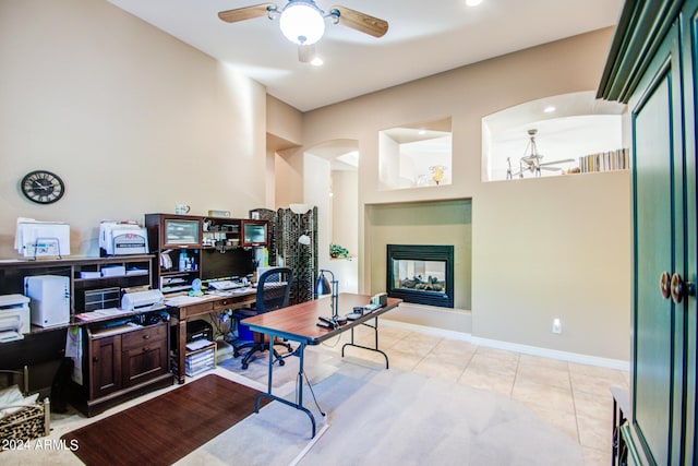 tiled home office featuring ceiling fan and a multi sided fireplace