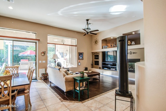 living room featuring light tile patterned flooring, built in features, and ceiling fan