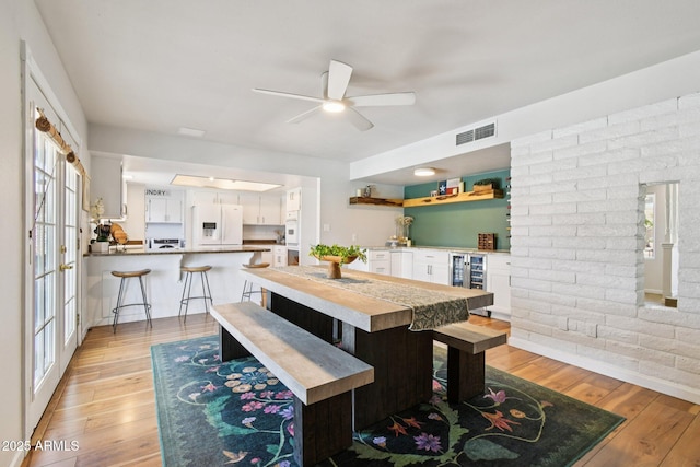 13842 N 40th Ave, Phoenix, AZ 85053 - dining space featuring a ceiling fan, light wood-style flooring, a bar, beverage cooler, and brick wall