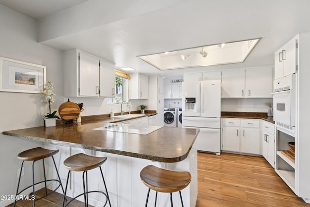 13842 N 40th Ave, Phoenix, AZ 85053 - kitchen featuring white refrigerator with ice dispenser, washer and dryer, a peninsula, dark countertops, and electric cooktop