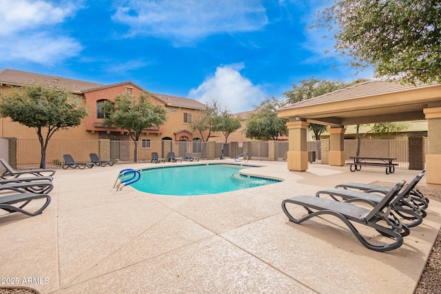 community pool with a patio area and fence