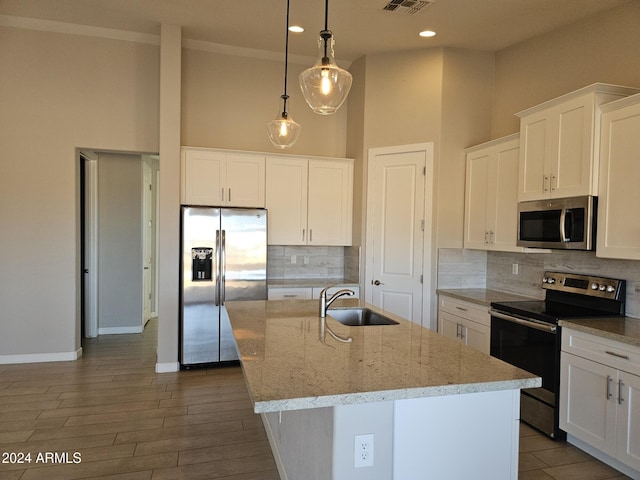 kitchen with stainless steel appliances, hanging light fixtures, a center island with sink, and sink