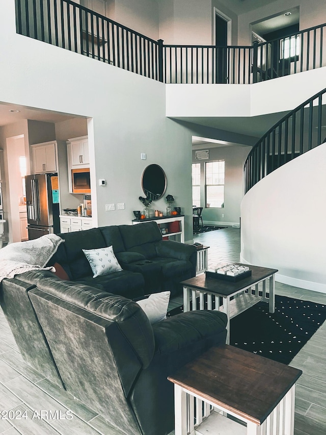 living room with light hardwood / wood-style floors and a towering ceiling