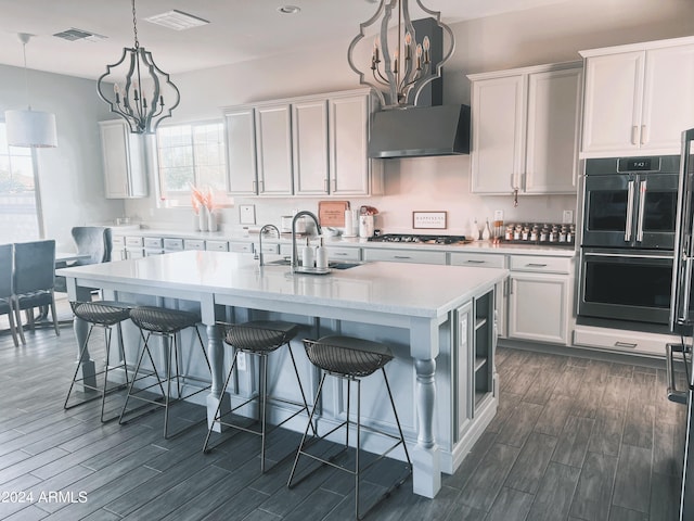 kitchen featuring white cabinetry, sink, an island with sink, and a notable chandelier