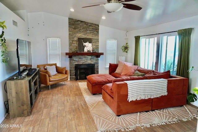 living room featuring ceiling fan, lofted ceiling, a fireplace, and light hardwood / wood-style flooring