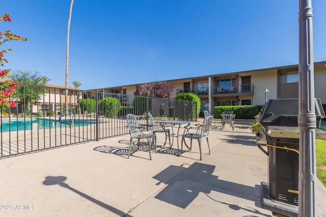 view of patio with a grill, fence, and a community pool