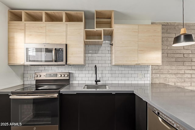 kitchen with appliances with stainless steel finishes, a sink, light brown cabinets, and light countertops