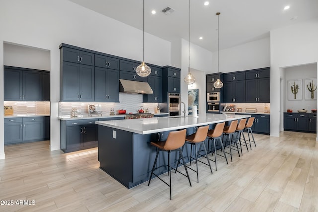 kitchen featuring decorative backsplash, a breakfast bar area, a high ceiling, hanging light fixtures, and a large island