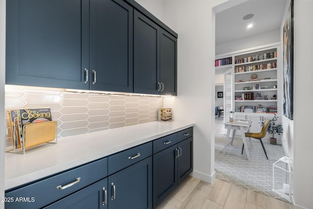 kitchen featuring backsplash, built in features, light hardwood / wood-style flooring, and blue cabinets