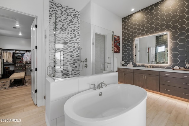 bathroom featuring vanity, tile walls, and shower with separate bathtub