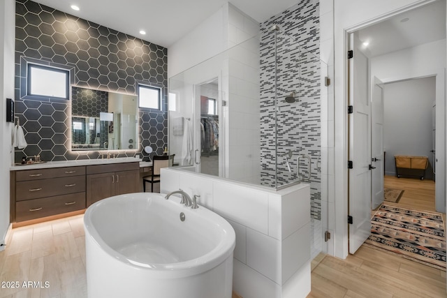 bathroom featuring vanity, independent shower and bath, and tile walls