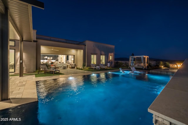 pool at twilight with outdoor lounge area, a patio, and pool water feature