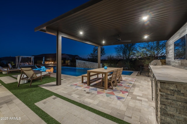 patio at twilight featuring ceiling fan and a bar