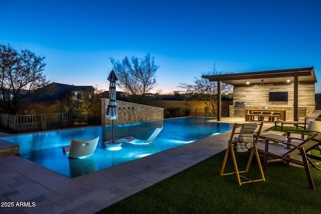 pool at dusk with area for grilling, a water slide, a patio, and grilling area