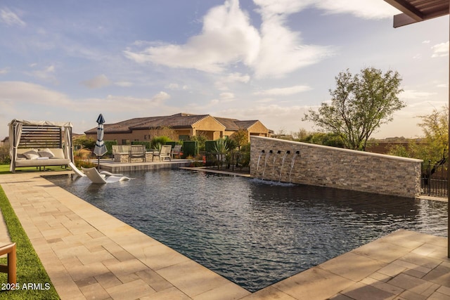 view of swimming pool with pool water feature and a patio