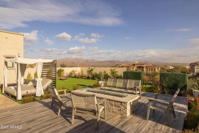 wooden deck with a mountain view, an outdoor living space with a fire pit, and a lawn