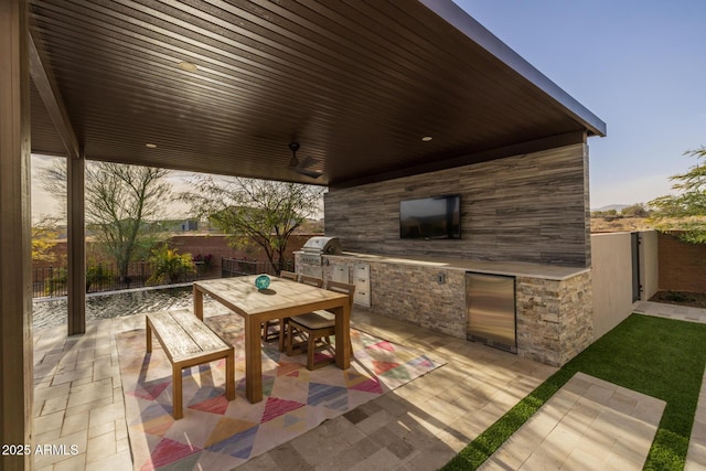 view of patio / terrace featuring ceiling fan, area for grilling, and exterior kitchen