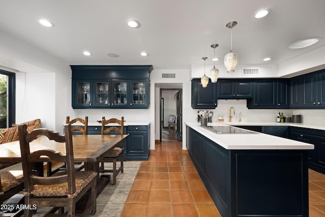 kitchen featuring black electric stovetop, blue cabinetry, light tile patterned floors, decorative light fixtures, and a center island