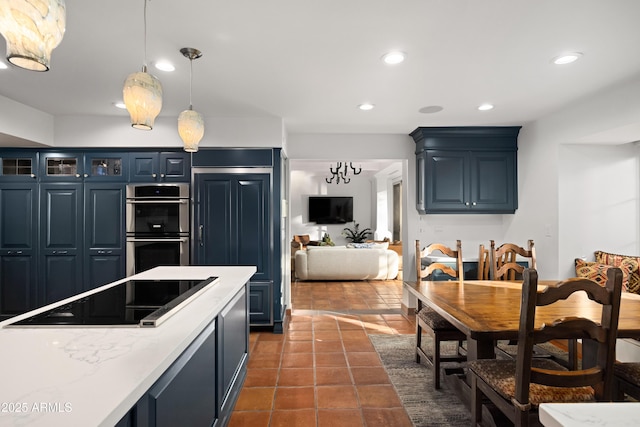 kitchen featuring stainless steel double oven, black electric cooktop, blue cabinets, paneled built in refrigerator, and hanging light fixtures