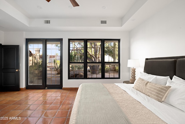 tiled bedroom with ceiling fan, a raised ceiling, and multiple windows