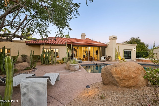 back house at dusk with a patio area