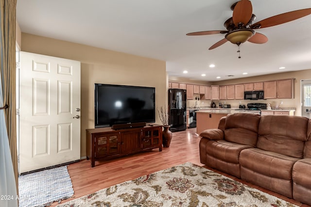 living room with ceiling fan and light hardwood / wood-style flooring