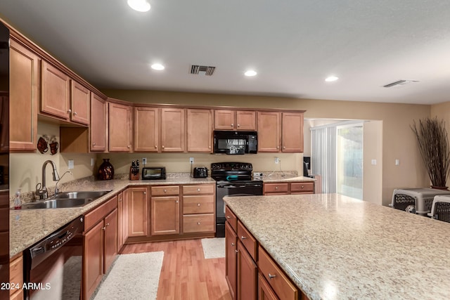 kitchen with sink, black appliances, and light hardwood / wood-style floors