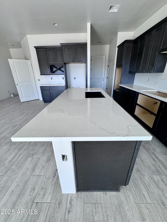 kitchen with white cabinets, a center island, and light hardwood / wood-style flooring