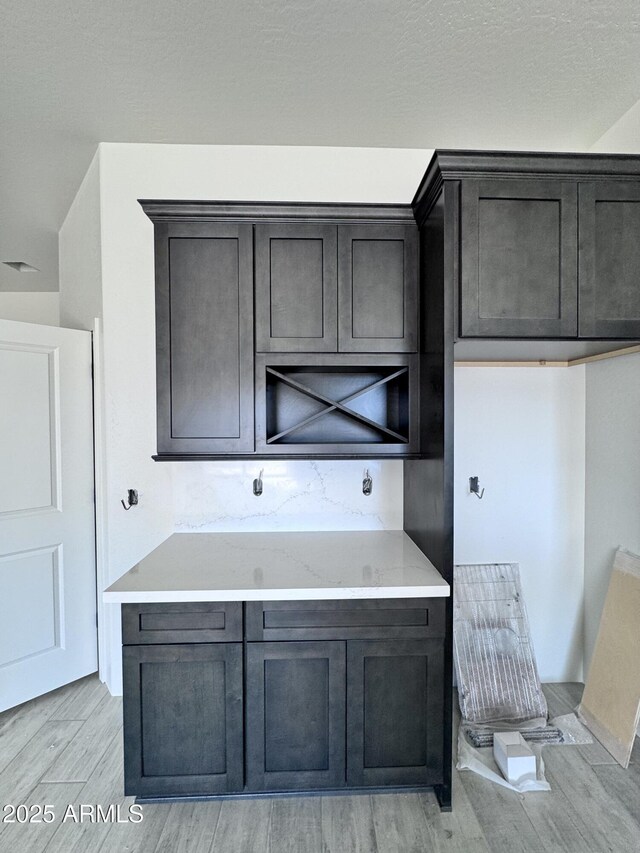 kitchen with a kitchen island, light stone countertops, white cabinetry, and light hardwood / wood-style flooring