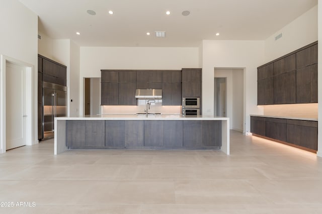 kitchen with light countertops, built in refrigerator, modern cabinets, and a sink