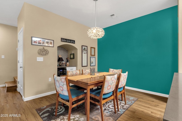3221 N 37th St Unit 10, Phoenix, AZ 85018 - dining space with wood finished floors, arched walkways, baseboards, and a chandelier