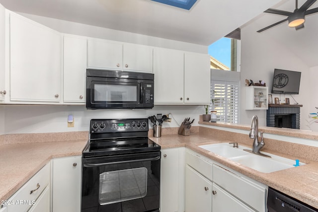 kitchen with black appliances, white cabinets, and a brick fireplace