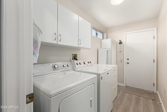 laundry area with light wood-type flooring, cabinets, and washer and dryer