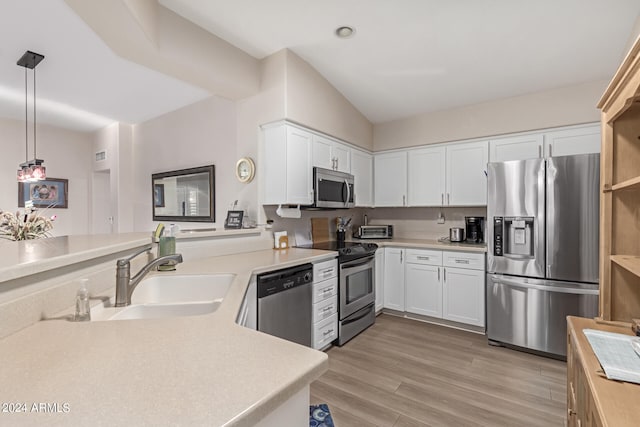 kitchen with stainless steel appliances, light hardwood / wood-style floors, white cabinetry, sink, and pendant lighting