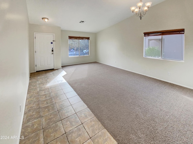 carpeted foyer with an inviting chandelier and lofted ceiling