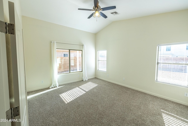 carpeted empty room with vaulted ceiling, plenty of natural light, and ceiling fan