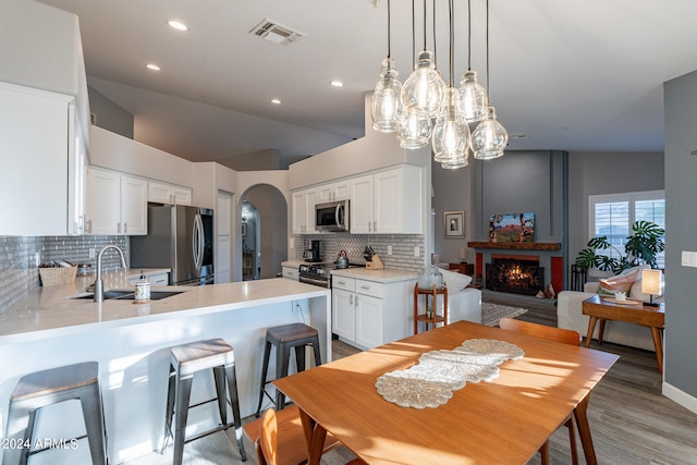 kitchen with white cabinets, sink, hardwood / wood-style flooring, stainless steel appliances, and decorative backsplash